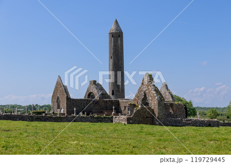 Kilmacduagh Abbey ruins in Galway with tall round tower ancient stone church surrounded by fields 119729445