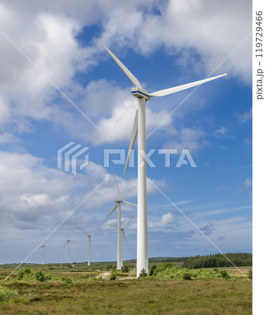Wind turbines in Ireland recede into distance over fields endless sky representing renewable energy Wind turbines in Ireland recede into distance over fields endless sky representing renewable energy 119729466