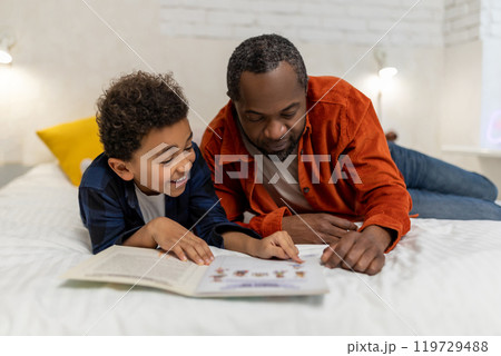 Dark-skinned man looking at the pictures in the boom together with his son 119729488