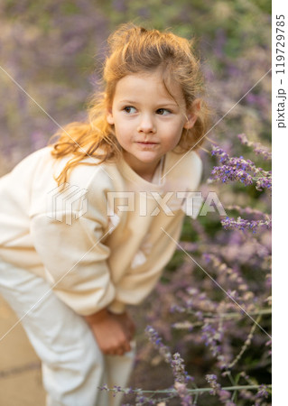 Little girl walking in the park in autumn and touching flowers in the garden. A cute girl in white clothes is standing in a flower alley. Little girl walking in the park in autumn and touching flowers in the garden. A cute girl in white clothes is standing in a flower alley. 119729785