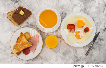 Morning breakfast, ham, eggs, toast, chocolate, juice, coffee on the table from top view 119730287