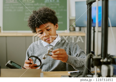 African American child engaging in engineering activity in classroom, carefully examining and handling mechanical parts while focusing on the task African American child engaging in engineering activity in classroom, carefully examining and handling mechanical parts while focusing on the task 119731851