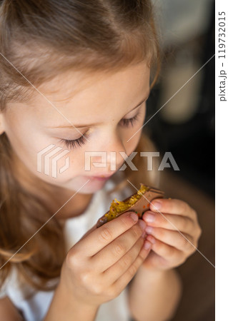 Little girl eating Dubai chocolate with pistachio paste and kataifi dough. Confectionery handmade sweets at home in the kitchen. Little girl eating Dubai chocolate with pistachio paste and kataifi dough. Confectionery handmade sweets at home in the kitchen. 119732015