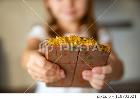 Dubai chocolate with pistachio paste and kataifi dough in hands of little girl. Confectionery handmade sweets at home in the kitchen. Dubai chocolate with pistachio paste and kataifi dough in hands of little girl. Confectionery handmade sweets at home in the kitchen. 119732021