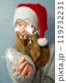 Heart shaped bengal fire in hand beautiful girl with long red hair New Year hat on grey background  119732231