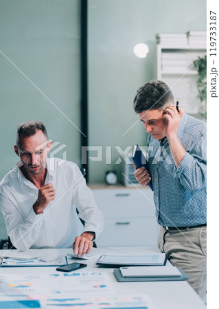 Two businessmen working together Analyze financial reports with charts and graphs while using the calculator to calculate budget, income, taxes, business growth. Startup business idea. Two businessmen working together Analyze financial reports with charts and graphs while using the calculator to calculate budget, income, taxes, business growth. Startup business idea. 119733187