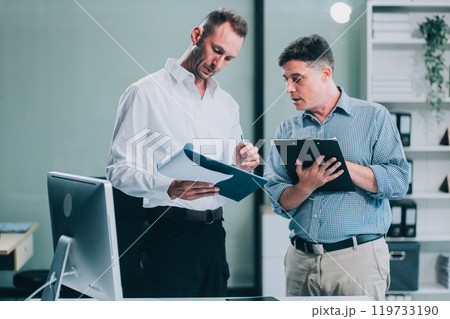 Two businessmen working together Analyze financial reports with charts and graphs while using the calculator to calculate budget, income, taxes, business growth. Startup business idea. Two businessmen working together Analyze financial reports with charts and graphs while using the calculator to calculate budget, income, taxes, business growth. Startup business idea. 119733190