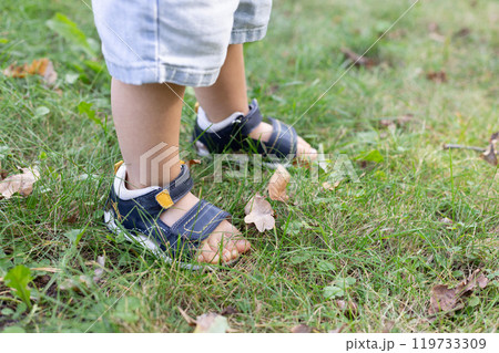 Little child walks in the park in too small sandals. Little child walks in the park in too small sandals. 119733309