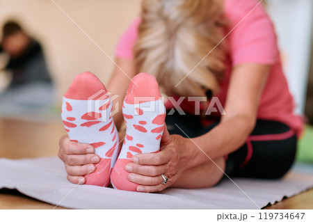 Senior Woman Practicing Back Stretches in a Sunlit Space for Optimal Health and Well Being 119734647