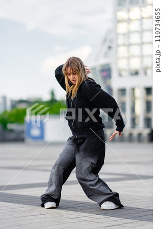 Young dancer practicing street style moves in an urban plaza setting Young dancer practicing street style moves in an urban plaza setting 119734655