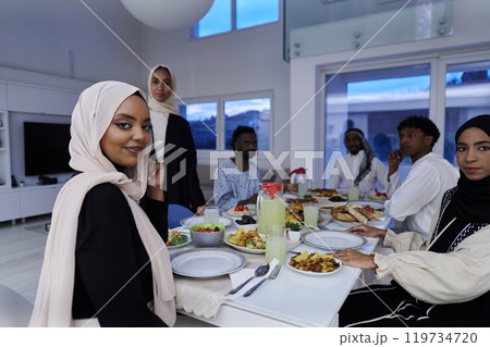 In the sacred month of Ramadan, a Muslim family joyously comes together around a table, eagerly awaiting the communal iftar, engaging in the preparation of a shared meal, and uniting in anticipation 119734720