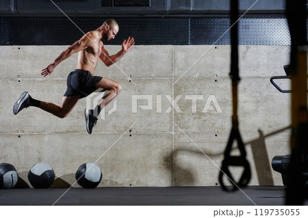 A muscular man captured in air as he jumps in a modern gym, showcasing his athleticism, power, and determination through a highintensity fitness routine 119735055