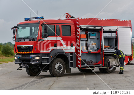 A firefighter meticulously prepares a modern firetruck for a mission to evacuate and respond to dangerous situations, showcasing the utmost dedication to safety and readiness in the face of a fire 119735182