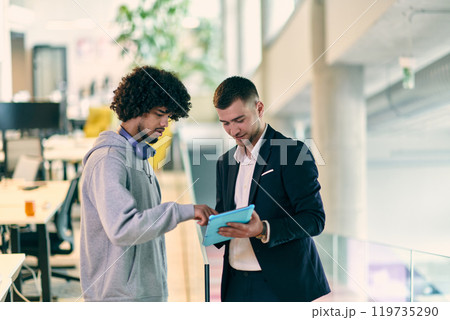 In a modern office setting, an African American businessman engages in a discussion with his director, using a tablet to address business challenges, symbolizing collaboration and technology In a modern office setting, an African American businessman engages in a discussion with his director, using a tablet to address business challenges, symbolizing collaboration and technology 119735290