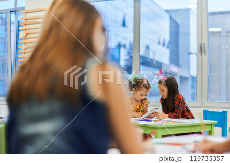 Creative kids during an art class in a daycare center or elementary school classroom drawing with female teacher. 119735357