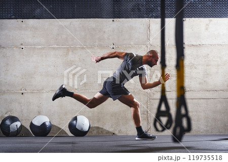 A muscular man captured in air as he jumps in a modern gym, showcasing his athleticism, power, and determination through a highintensity fitness routine A muscular man captured in air as he jumps in a modern gym, showcasing his athleticism, power, and determination through a highintensity fitness routine 119735518