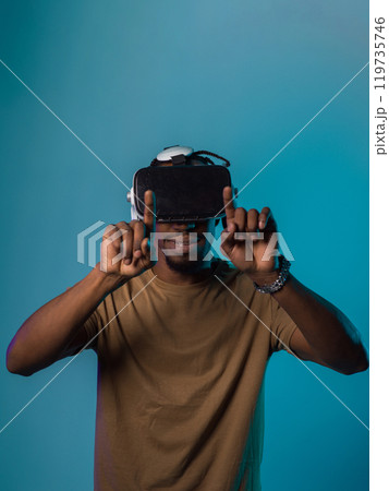 Immersed in a digital realm, an African American man navigates the virtual landscape with a VR goggles, using tactile gestures to interact with virtual objects, showcasing a harmonious blend of 119735746