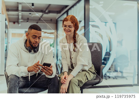 In a modern office African American young businessman and his businesswoman colleague, with her striking orange hair, engage in collaborative problem-solving sessions 119735975