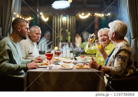 A group of family friends, comprising a young grandson and older individuals, share a delightful dinner in a modern restaurant, exemplifying the concept of healthy aging through intergenerational A group of family friends, comprising a young grandson and older individuals, share a delightful dinner in a modern restaurant, exemplifying the concept of healthy aging through intergenerational 119736068