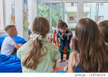 A happy female teacher sitting and playing hand games with a group of little schoolchildren 119736229