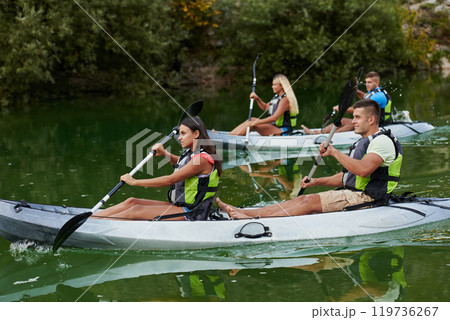 A group of friends enjoying having fun and kayaking while exploring the calm river, surrounding forest and large natural river canyons 119736267