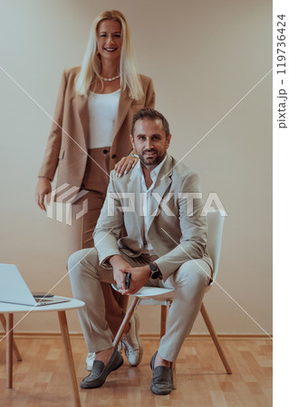 A business couple posing for a photograph together against a beige backdrop, capturing their professional partnership and creating a timeless image of unity and success. 119736424