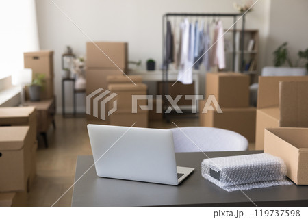 Laptop on table with belongings in boxes at new store Laptop on table with belongings in boxes at new store 119737598