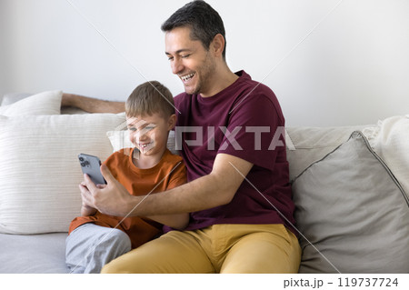 Happy father showing online content on mobile phone to son Happy father showing online content on mobile phone to son 119737724