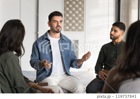 Serious male Middle Eastern group therapy patient talking to community Serious male Middle Eastern group therapy patient talking to community 119737841