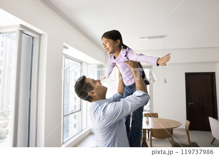 Joyful Indian father lifting girl up in air Joyful Indian father lifting girl up in air 119737986