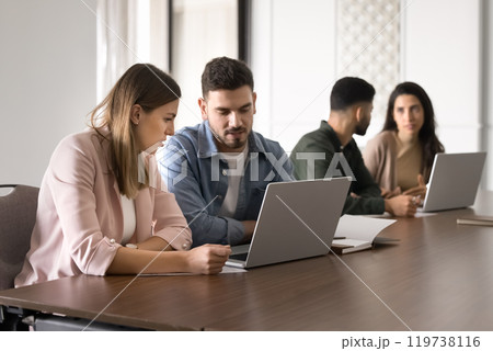 Couple of serious business colleagues sharing laptop for teamwork 119738116