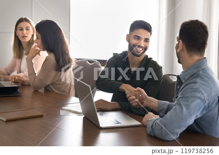 Cheerful young Arabic business professional shaking hands with partner Cheerful young Arabic business professional shaking hands with partner 119738256