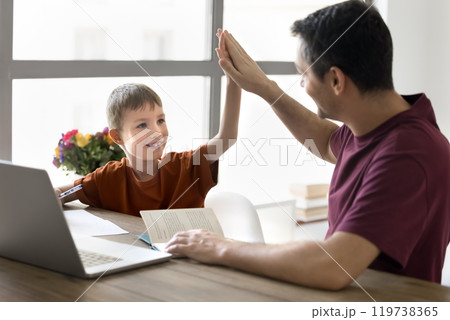 Happy schoolkid son and dad giving high five at home Happy schoolkid son and dad giving high five at home 119738365