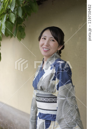 壁に立つ若い浴衣の女性 119738482
