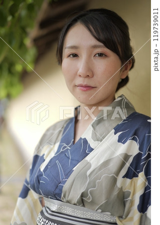 壁に立つ若い浴衣の女性 119739011