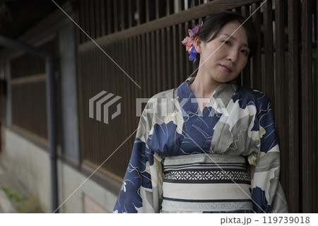 格子戸に立つ若い浴衣の女性 119739018