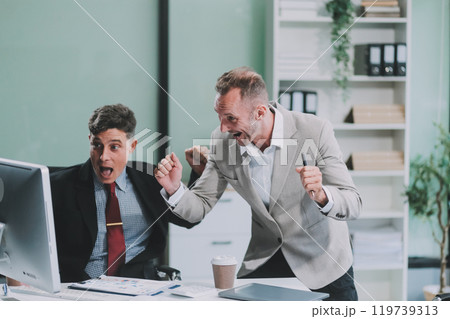 Two happy colleagues with laptop and documents in office Two happy colleagues with laptop and documents in office 119739313