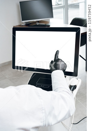 A person in gloves interacting with a touchscreen display in a modern office environment 119739452