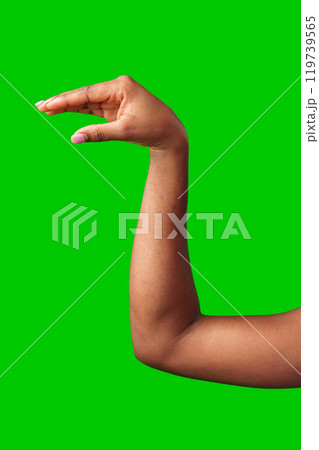 A hand making a gesture with a green background during daylight 119739565