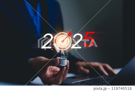 2025 business goals and strategy planning concept. Businessman holds lightbulb with a target symbol and "2025" displayed, goal setting, future business strategies, and action plans for the year 2025. 2025 business goals and strategy planning concept. Businessman holds lightbulb with a target symbol and "2025" displayed, goal setting, future business strategies, and action plans for the year 2025. 119740518