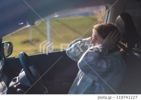 Caucasian woman holds hands on head while driving in panic.  119741227