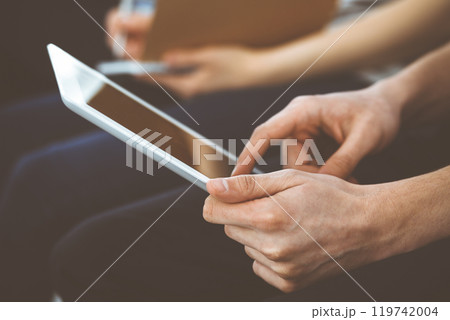 Group of casual dressed business people working at meeting or conference, close-up of hands. Businessman using tablet computer. Teamwork or coaching concept Group of casual dressed business people working at meeting or conference, close-up of hands. Businessman using tablet computer. Teamwork or coaching concept 119742004