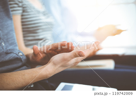 Business people clapping at meeting or conference, close-up of hands. Group of unknown businessmen and women in sunny office 119742009