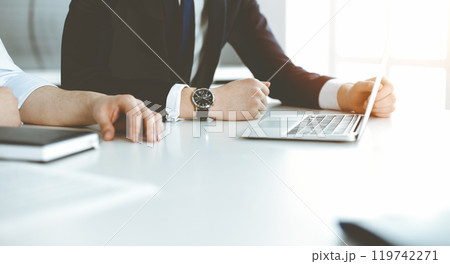 Unknown business people using laptop computer at the desk in modern office. Businessman or male entrepreneur is working with his colleague. Teamwork and partnership concept 119742271