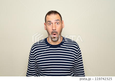 Hispanic man with beard about 40s scared and shocked with surprise expression, fear and excited face. Isolated on beige background. Hispanic man with beard about 40s scared and shocked with surprise expression, fear and excited face. Isolated on beige background. 119742325