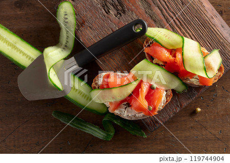 Sandwiches with smoked trout, cream cheese, fresh cucumber, and capers on a wooden table. Sandwiches with smoked trout, cream cheese, fresh cucumber, and capers on a wooden table. 119744904
