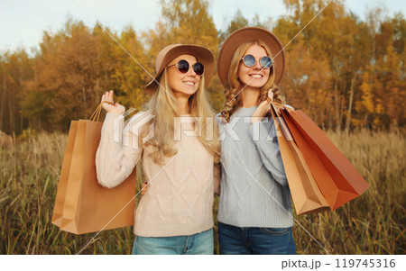 Fashionable happy two women friends with shopping bags, stylish smiling girlfriends in autumn park Fashionable happy two women friends with shopping bags, stylish smiling girlfriends in autumn park 119745316