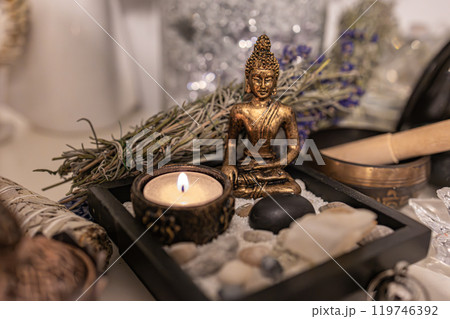 A peaceful home altar featuring a Buddha statue, burning candle, sage, and stones, creating a serene space for meditation, spirituality, and wellness. Ideal for zen, mindfulness, and calming environme A peaceful home altar featuring a Buddha statue, burning candle, sage, and stones, creating a serene space for meditation, spirituality, and wellness. Ideal for zen, mindfulness, and calming environme 119746392