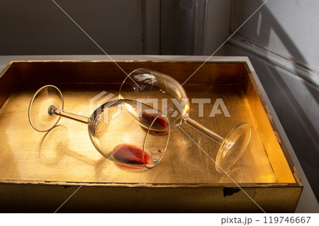 Used wine glasses, two half empty glasses of red wine on a golden tray background Used wine glasses, two half empty glasses of red wine on a golden tray background 119746667