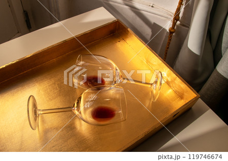 Used wine glasses, two half empty glasses of red wine on a golden tray background Used wine glasses, two half empty glasses of red wine on a golden tray background 119746674